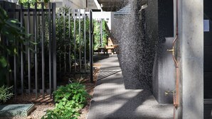 Een modern gebouw met een betonnen gevel, een waterpartij en een metalen hek.