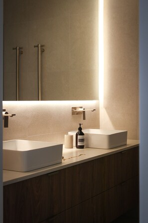 Ein modernes Badezimmer mit zwei Waschbecken, einem Spiegel und einer Seife.