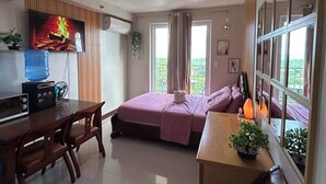 Una camera moderna con un letto, una scrivania, una televisione e un'ampia finestra.