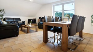 Un salon moderne avec une table à manger, deux canapés et une grande fenêtre.