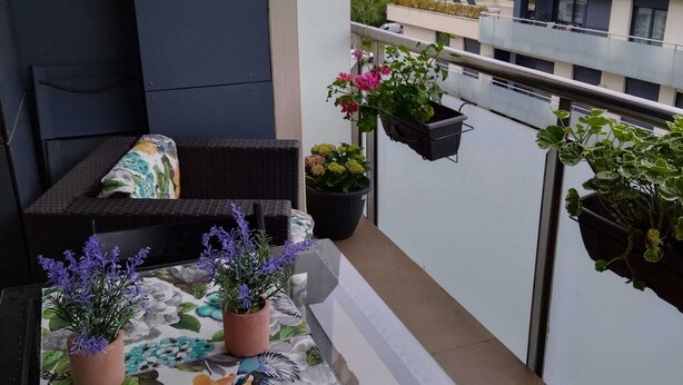 A balcony with a table, chairs, and potted plants. - Zoreda Apartment (Unknown)