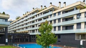 A multi-story residential building with a swimming pool and a small tree in the courtyard. - Zoreda Apartment (Unknown)