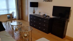 A living room with a sofa, a glass coffee table, a TV, a dresser, and a decorative wall piece. - Zoreda Apartment (Unknown)