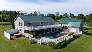 A large two-story house with a green roof, a covered patio, and a swimming pool. - Firefly Farms – Mohawk Valley (Fultonville)