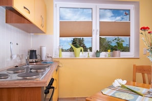 Una cocina con estufa, lavabo y ventana con persianas.