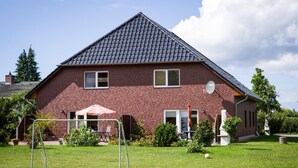 A two-story brick house with a sloped roof, a satellite dish, and a visible satellite dish on the side. - Apartment 'Schwälbchen' with Shared Garden and Wi-Fi (Fuhlendorf)
