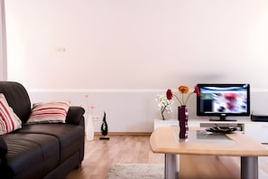 Una sala de estar moderna con un sofá, una mesa de centro, un televisor y objetos decorativos.