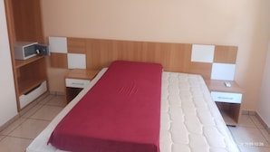 Un dormitorio con cama, armario de madera, mesita de noche y un cuadro en la pared.