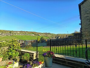 A balcony with a view of a rural landscape, including fields and a wind turbine. - Steam View Cottage (Keighley)
