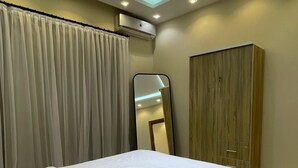 Ein modernes Hotelzimmer mit einem ordentlich bezogenen Bett, einer Klimaanlage, einem Kleiderschrank und einem Spiegel.