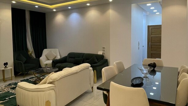 Ein modernes Wohnzimmer mit einer Couch, Sesseln und einem Esstisch.