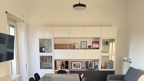 A modern living room with a dining area, white cabinetry, and a grey sofa. - The Monteverde Penthouse (Roma)