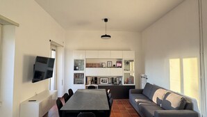 A modern living room with a dining table, sofa, and TV mounted on the wall. - The Monteverde Penthouse (Roma)