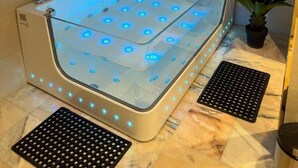 A modern spa tub with blue LED lights, a potted plant, and a marble floor. - Ferbion hotel (Muhayil)