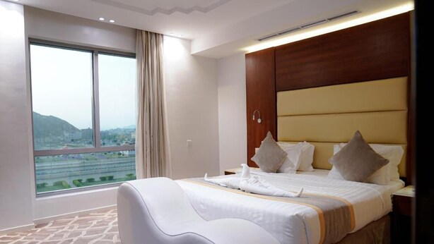 A hotel room with a large bed, a view of the city, and a modern design. - Ferbion hotel (Muhayil)