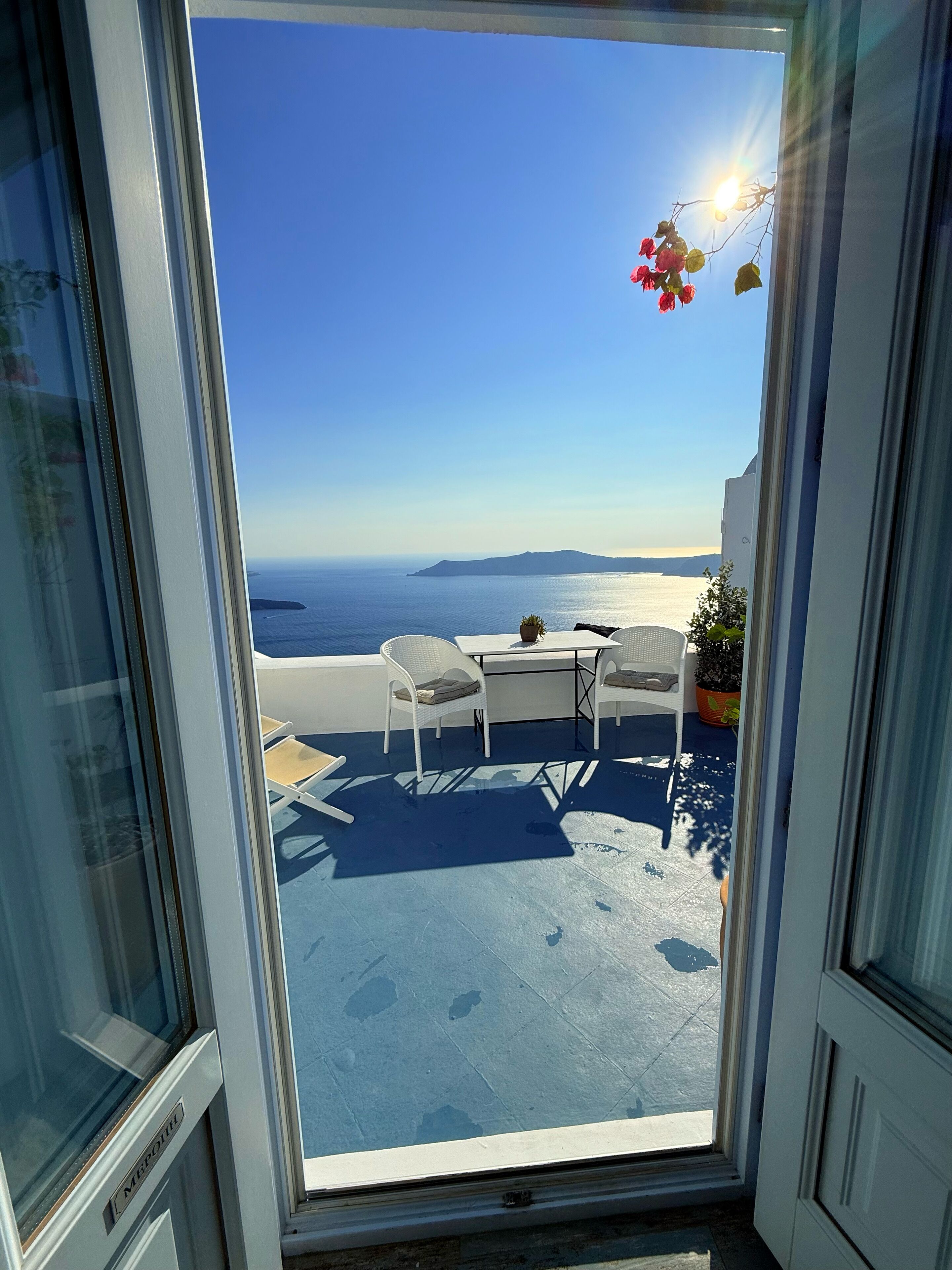 Un balcon avec vue sur la mer, une table et deux chaises.