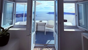A room with a view of the sea, a small table, a white chair, and a potted plant. - Sunset Caldera Sea View Houses  (Santorini)
