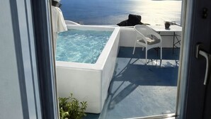 A room with a view of the sea, a hot tub, and a small table with a chair. - Sunset Caldera Sea View Houses  (Santorini)