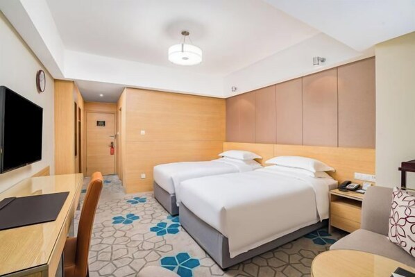 Une chambre d’hôtel équipée d’un lit, d’un bureau, d’une chaise, d’une télévision et d’une horloge.