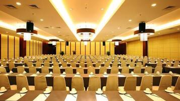 Un salón de conferencias con filas de mesas y sillas, equipado con tarjetas de identificación y posavasos.