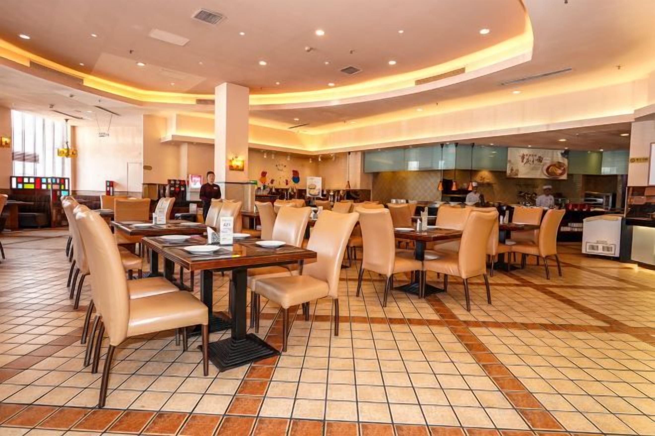 Un restaurante amplio con múltiples mesas y sillas, suelo de baldosas y una decoración moderna.