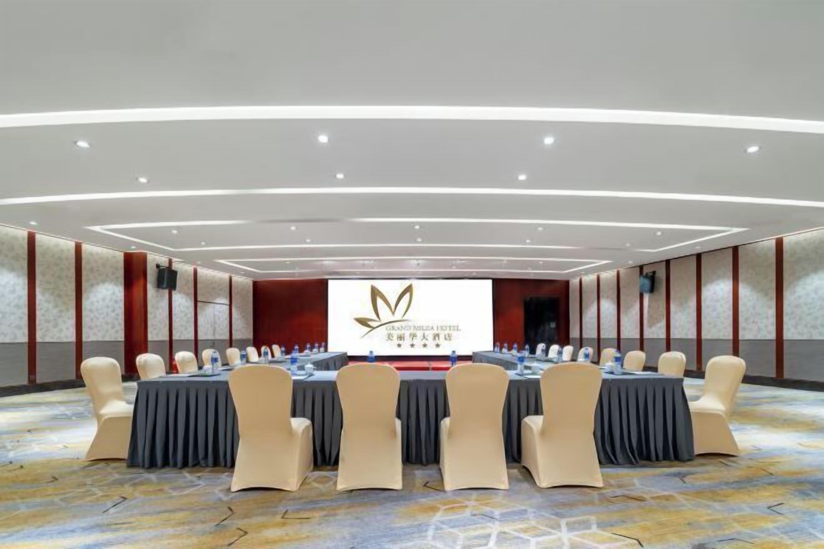 A conference room with a long table and chairs, a large screen, and a carpeted floor.