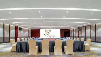 A conference room with a long table and chairs, a large screen, and a carpeted floor.