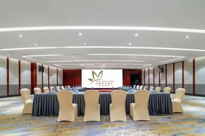 Une salle de conférence avec une longue table et des chaises, un grand écran et un sol recouvert de moquette.