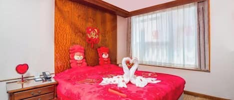 Una camera d'albergo con un letto grande, una testiera in legno, un comodino e una finestra con tende.