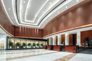 A spacious lobby with a reception desk, seating area, and a large plant display.