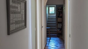 A narrow hallway with tiled flooring, a framed sign on the wall, and a window at the end. - Provencal house with pool and garden in the Aix countryside (puyricard)