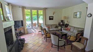 A living room with a fireplace, a sofa set, a coffee table, and a dining table. - Provencal house with pool and garden in the Aix countryside (puyricard)