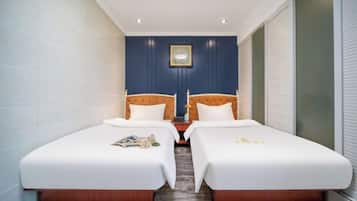 Quarto de hotel com duas camas de solteiro, uma mesa pequena e um quadro pendurado na parede.