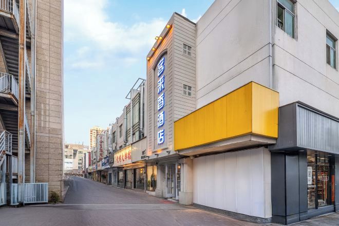 A street view of a building with multiple commercial establishments, including a hotel with a prominent sign.