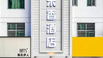 A hotel sign with vertical text, a white facade, and a yellow section on the right.