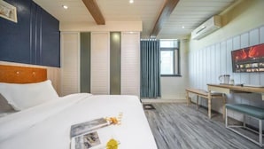 Une chambre d’hôtel avec un lit, un bureau, une banquette et un téléviseur.