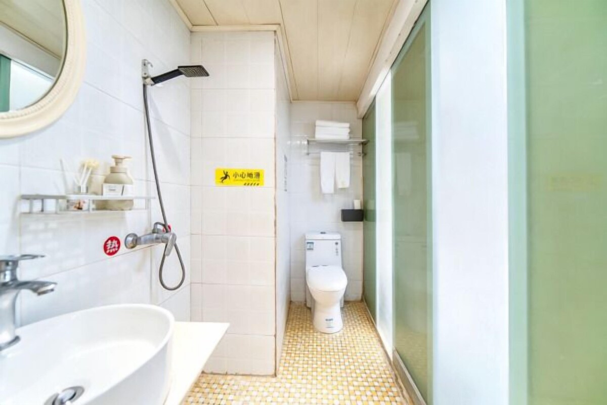 A compact bathroom with a sink, toilet, and shower.