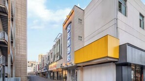Un hôtel moderne, reconnaissable à sa façade jaune éclatante et à une enseigne indiquant qu’il s’agit d’un hôtel.