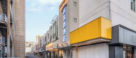 Un hotel moderno con una fachada amarilla destacada y un letrero que indica que es un hotel.