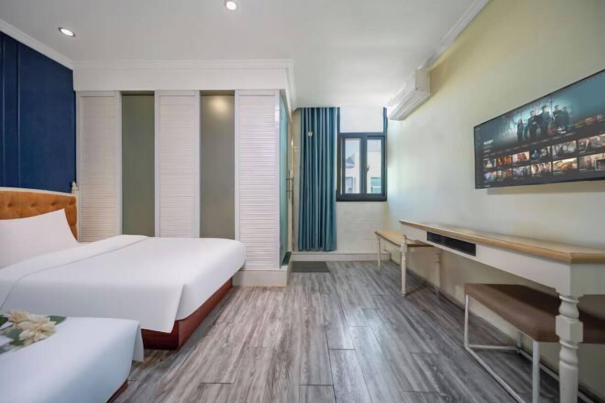 A hotel room with a bed, a desk, a chair, and a large window.