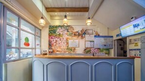 Un espace d’accueil avec un comptoir, des certificats encadrés et une fresque murale.