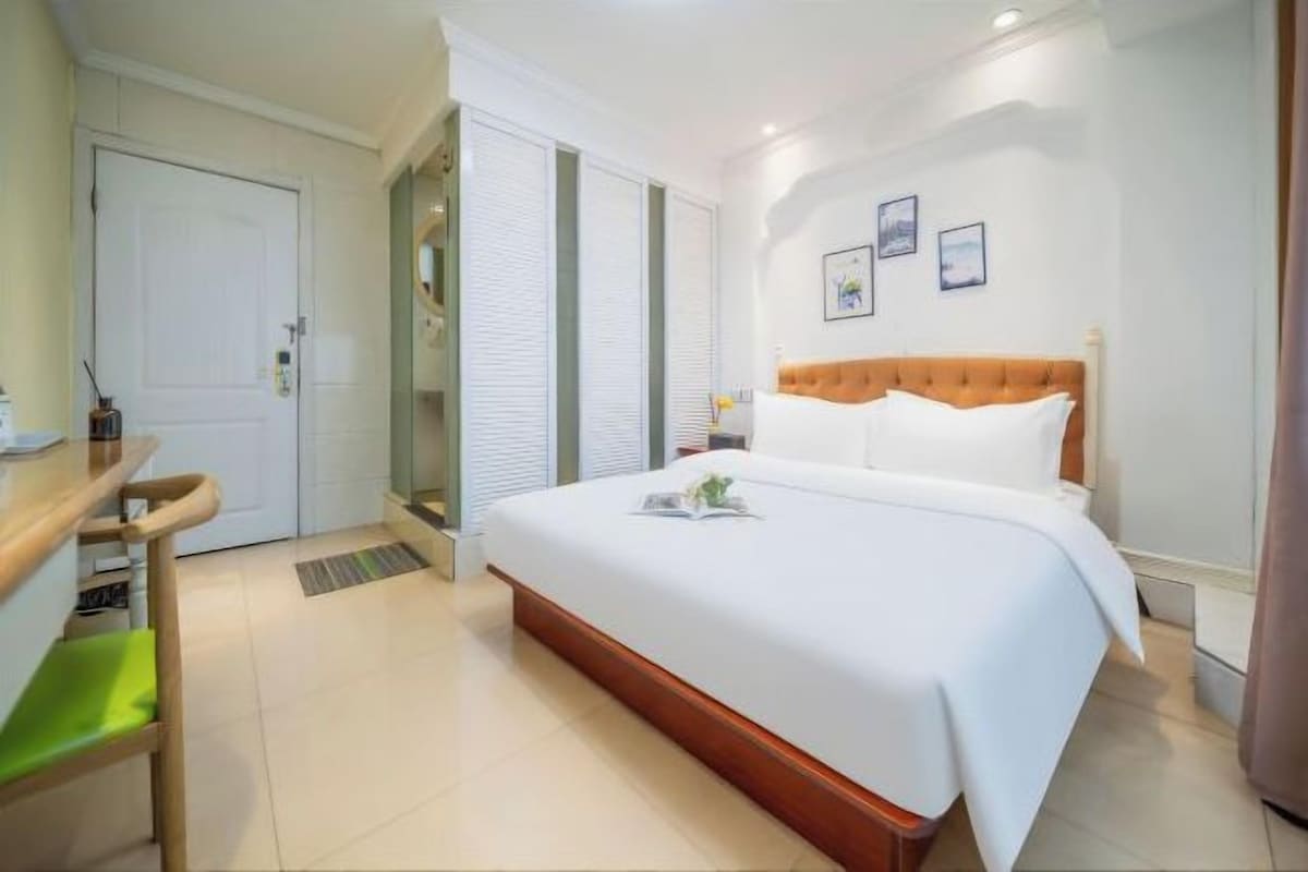 Una habitación de hotel con cama, mesita de noche, una silla y una puerta.