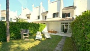 Un immeuble résidentiel doté d’un patio comprenant un barbecue, des chaises longues et une table à manger.