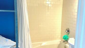 Une salle de bain avec une baignoire, des carreaux blancs, un mur bleu et une serviette blanche sur le sol.