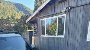Ein weißes Auto vor einem Holzgebäude mit Garagentür und Fenster.