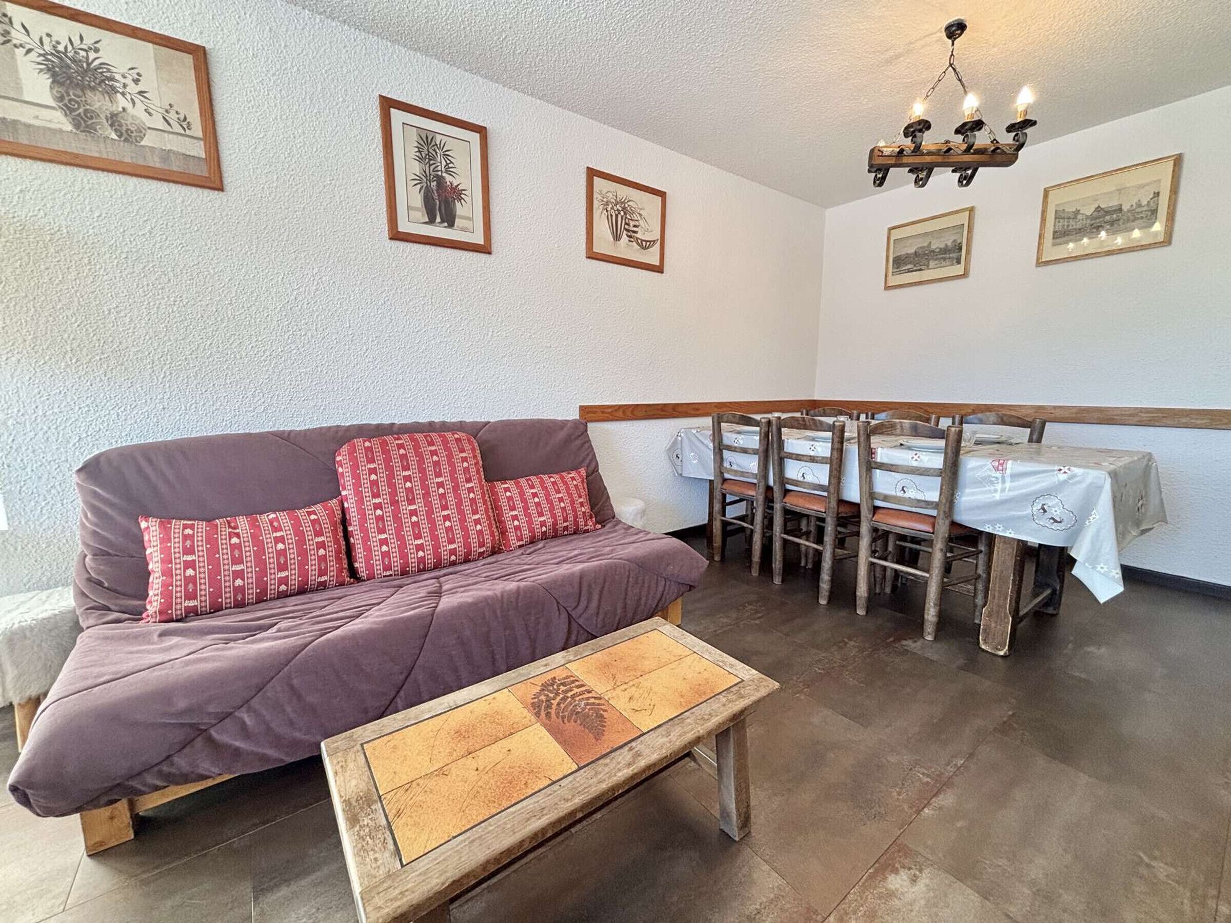 Une pièce chaleureuse avec un canapé, une petite table en bois et un coin repas comprenant des chaises et une table.