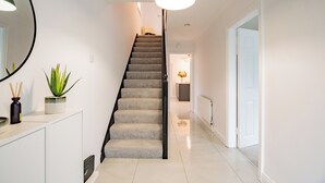Eine Treppe mit einer Lampe darüber, einem Blumentopf und einem Schrank mit Spiegel.