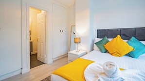 Ein Hotelzimmer mit einem Bett, einem Nachttisch, einer Lampe und einer Tür zu einem Badezimmer.