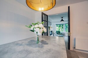 Una cocina moderna con una isla grande, un jarrón de flores blancas y vistas al comedor.