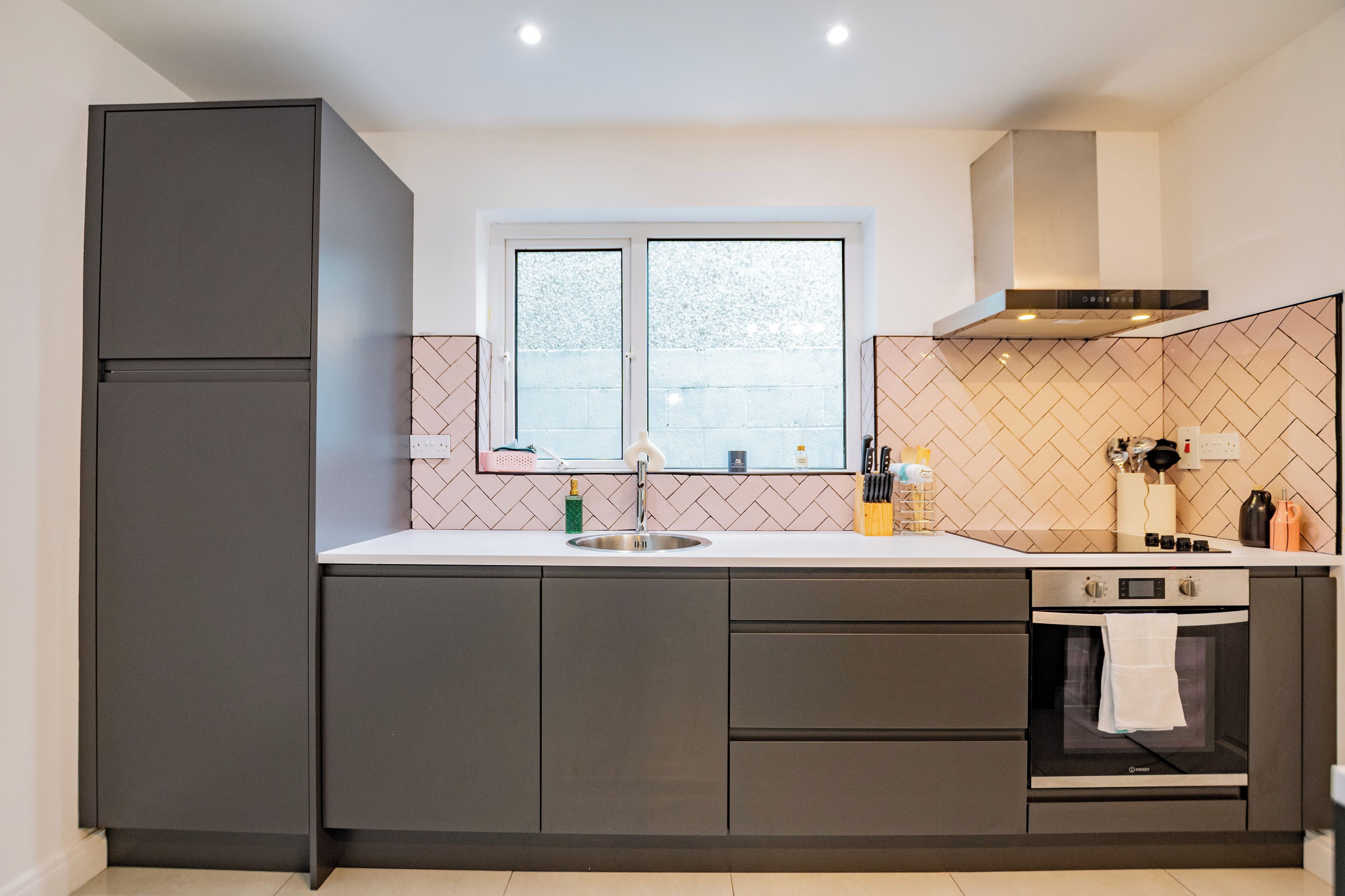 A modern kitchen with a double sink, a built-in oven, and a window above the sink.